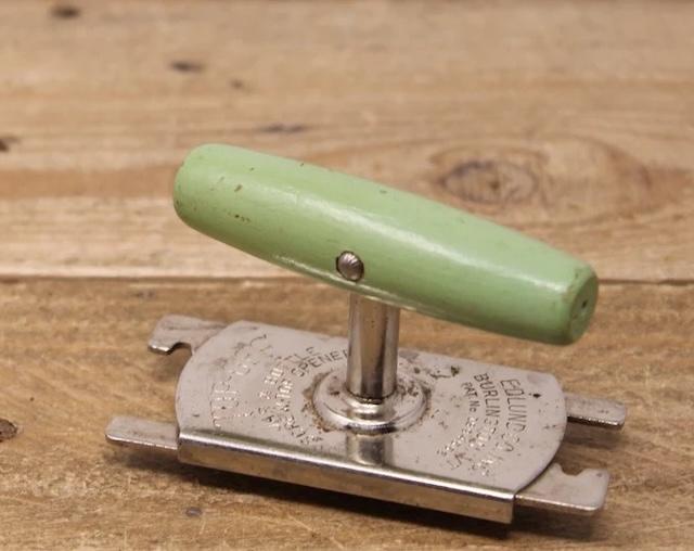 A charming vintage jar opener with a green handle, showcasing the variety of designs available during its time.