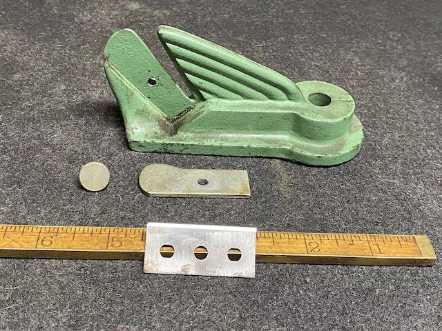 The disassembled parts of the leather strap cutter displayed, including the blade and measurement ruler, indicating the precision craftsmanship of older tools