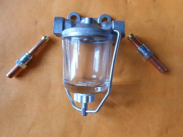 Displaying the glass bowl filter alongside accompanying parts, showcasing the full setup that was crucial for maintaining fuel purity in vintage vehicles