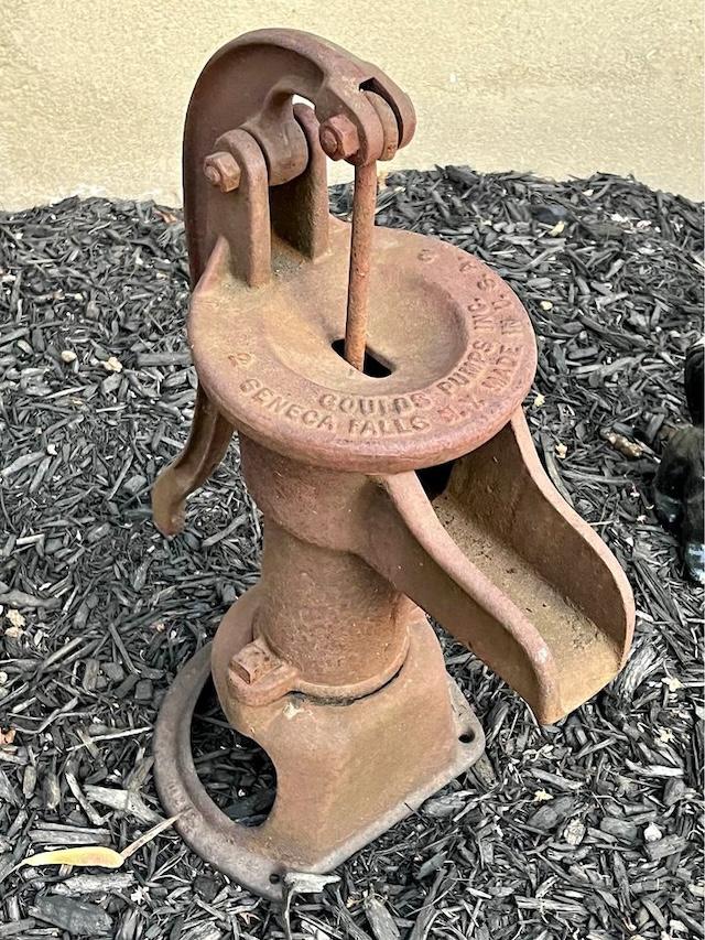 A close-up of a classic Fairbury hand pump, its rusted body a testament to the robust engineering of a bygone time.