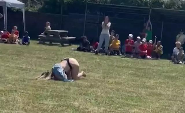 Katie Hannaford, caught mid-fall, becomes the center of attention as onlookers react to the unexpected and hilarious wardrobe malfunction at the school sports event