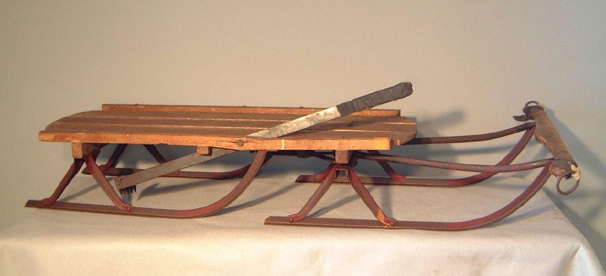 The iconic red metal frame and wooden seat of this sled symbolize a nostalgic reminder of simpler times