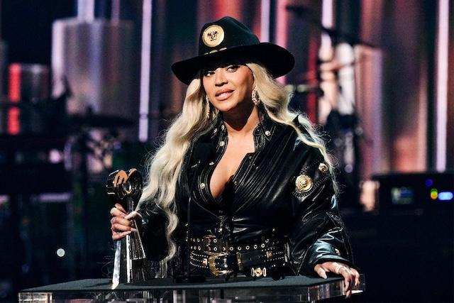 Beyoncé accepting an award in a bold black outfit, showcasing her unapologetic style and artistry