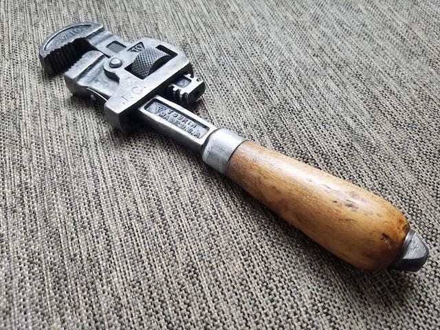 A well-preserved example of a vintage Stillson wrench, showcasing the smooth wooden handle that provided a comfortable grip for users over the years