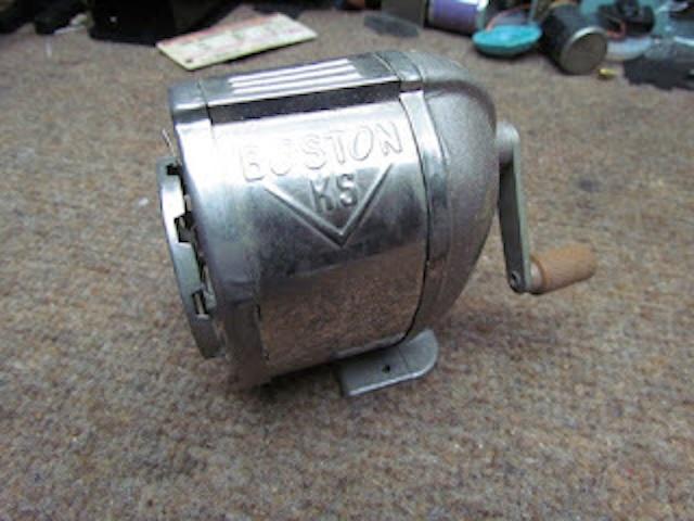 A side view of the Boston Model KS Pencil Sharpener, highlighting its robust metal casing and crank handle