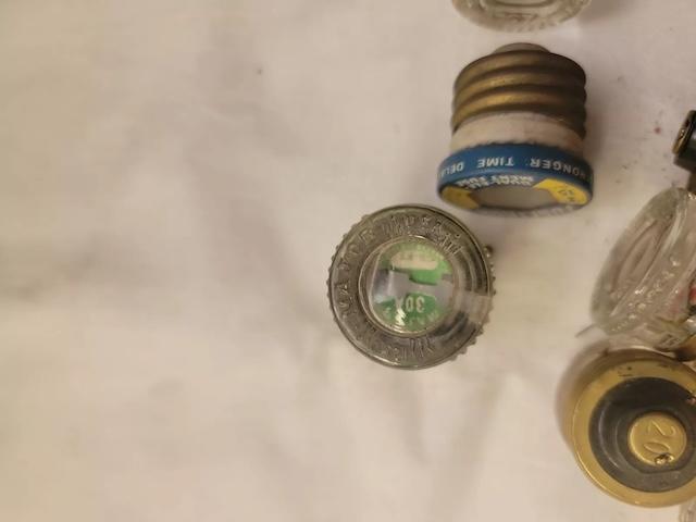 A closer look at different vintage glass fuses, revealing labels and markings that hint at their specific uses in electrical systems