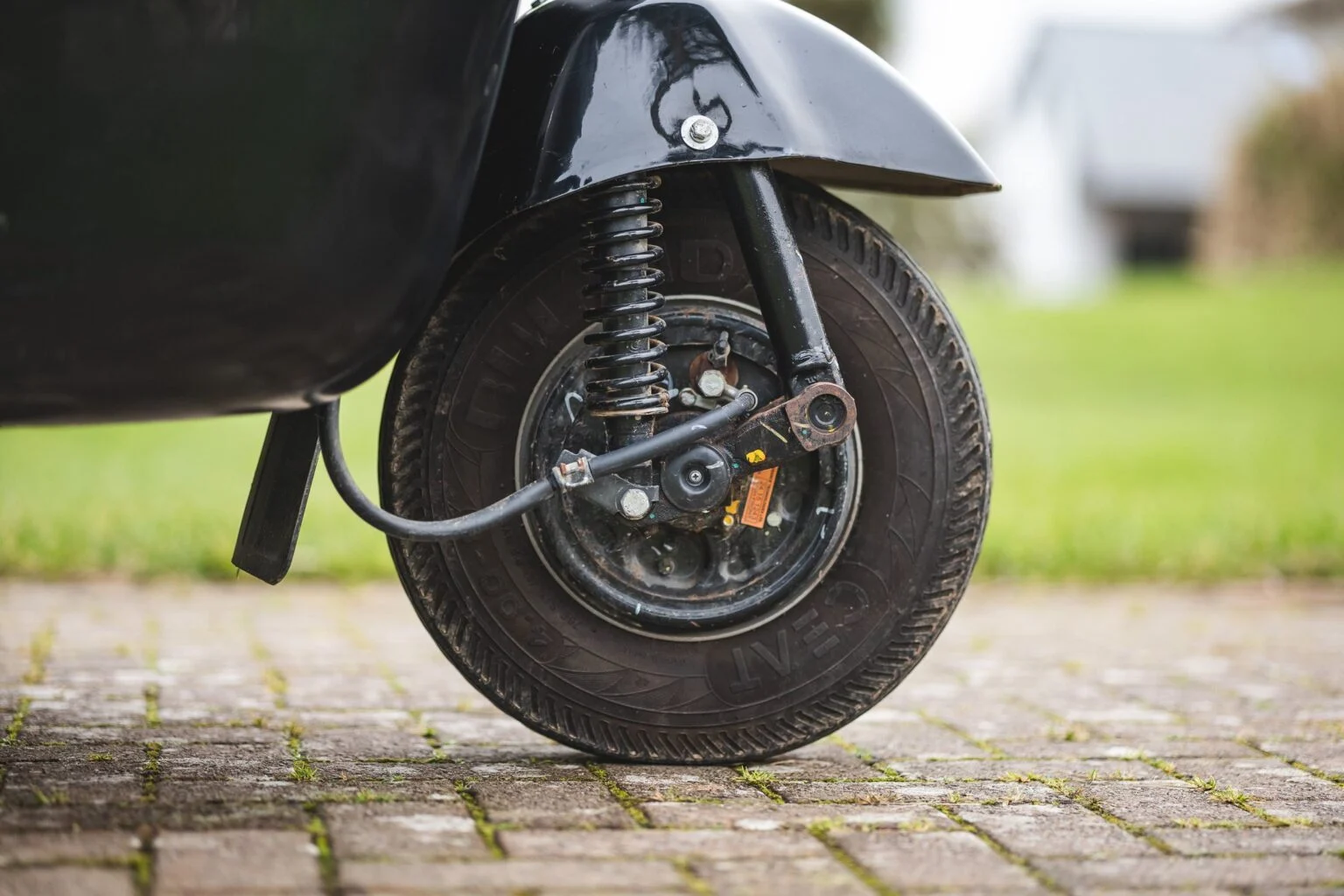 Close-up view of the rear wheel and suspension system on the Bajaj Tuk Tuk, highlighting its compact and functional design for urban maneuverability.