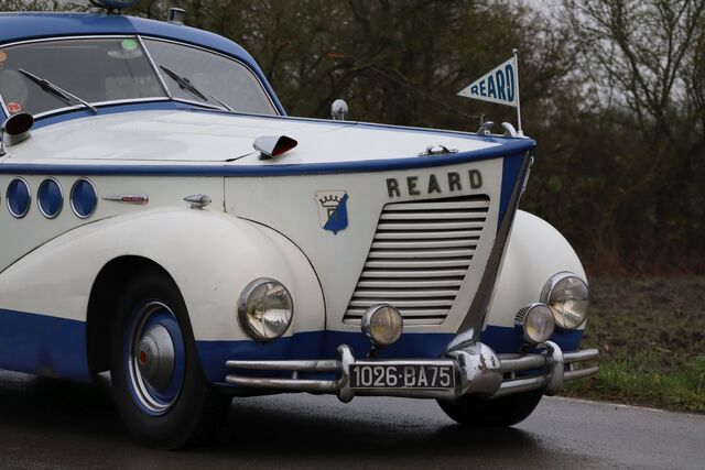 The car features Louis Réard's branding, proudly displayed on the large flag on the roof, continuing the fusion of fashion and function.