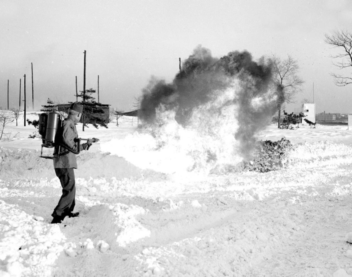 Tired of endless shoveling, a man takes an unconventional approach—using a flamethrower to carve a path through the frozen streets of Governors Island, 1947.