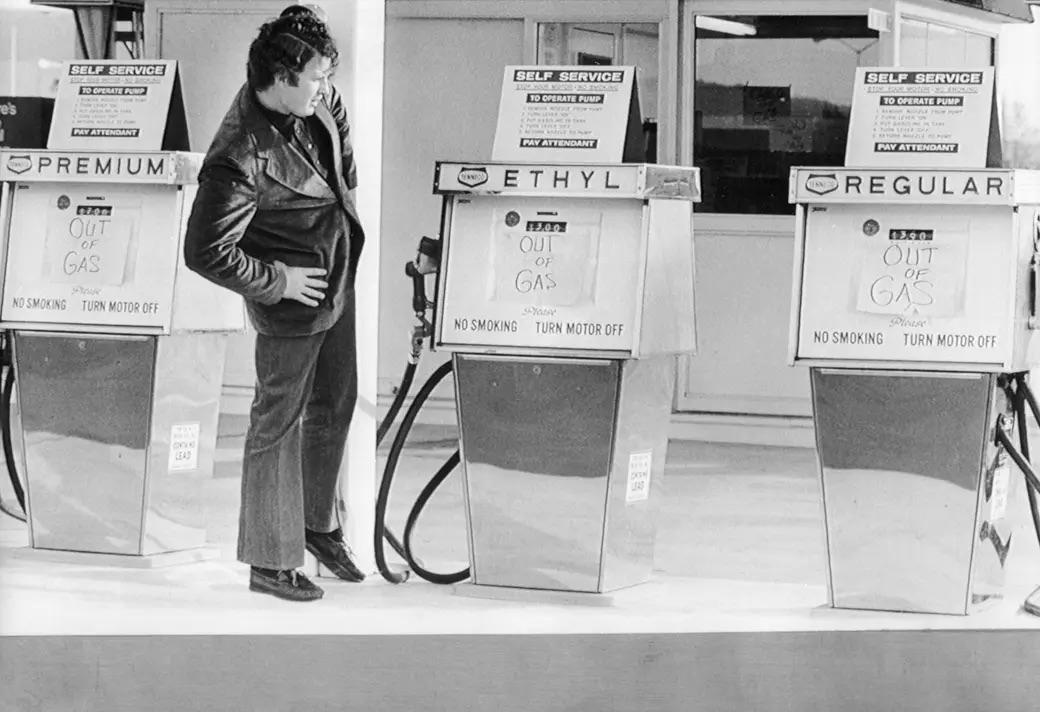 A man stands in disbelief before the "out of gas" signs on Tenneco's self-service pumps—a candid glimpse into the fuel crisis era.
