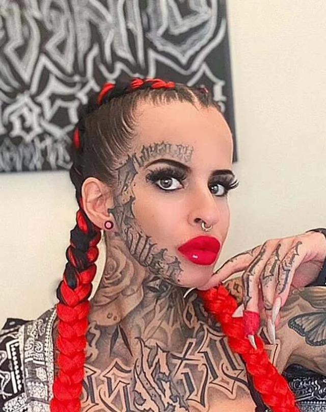 A close-up of Toxii showing off her vivid red hair and detailed tattoos, emphasizing her bold style.