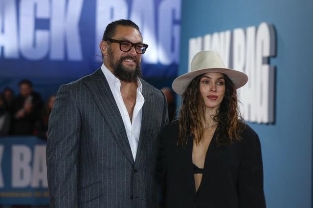 Another snap of Jason Momoa and Adria Arjona at the Black Bag movie screening, this time captured in front of the promotional banner.