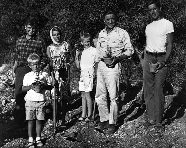 A candid family moment in 1965: Kirk Douglas with wife Anne and his four sons—Joel, Peter, Eric, and Michael—while gardening outdoors.