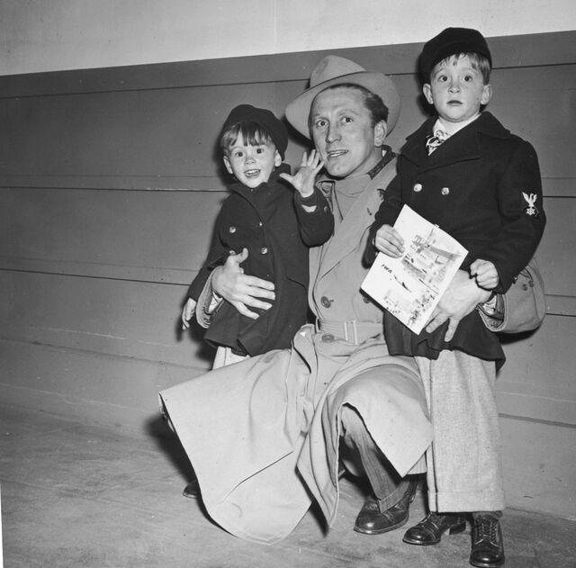 In 1955, Kirk Douglas kneels beside his sons, Joel (left) and Michael (right), in a candid family shot.