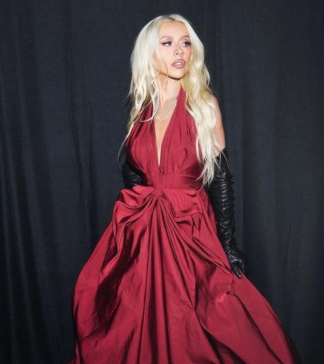 In another, she strikes a bold pose in a sheer bodysuit, black bra, and long black gloves, exuding confidence with daring makeup that demands attention.