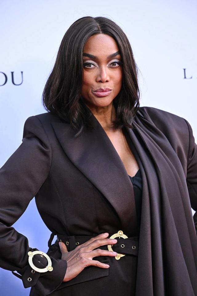 Tyra donned a dark brown ankle-length coat cinched at the waist with a belt, exuding an air of effortless elegance.