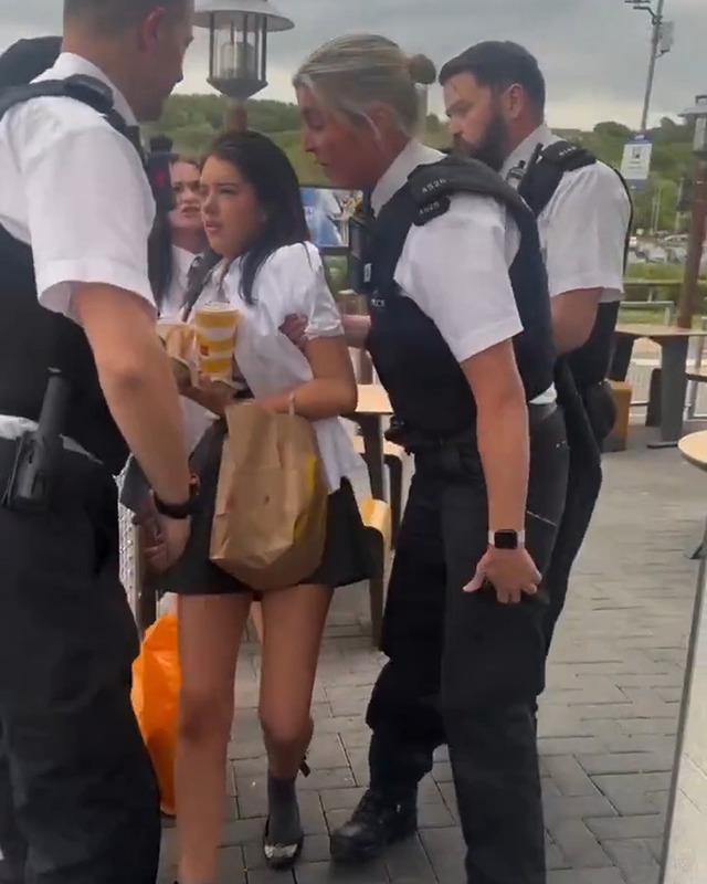 Three police officers close in on the 13-year-old girl outside McDonald’s as the tense confrontation unfolds in front of onlookers.