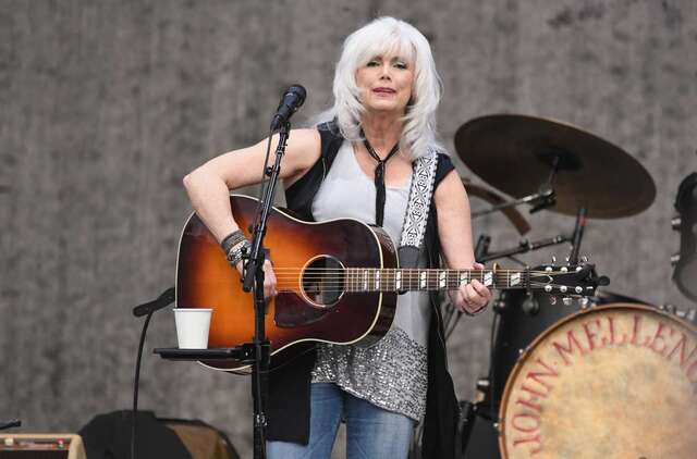 A dynamic moment on stage as Emmylou performs with her signature guitar, captivating the audience with her iconic sound.