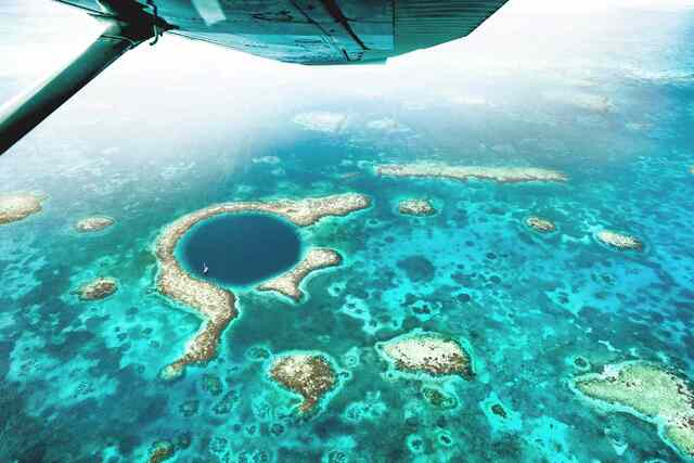 Aerial view of the Great Blue Hole, Belize, showcasing its deep blue circle surrounded by vibrant turquoise waters.