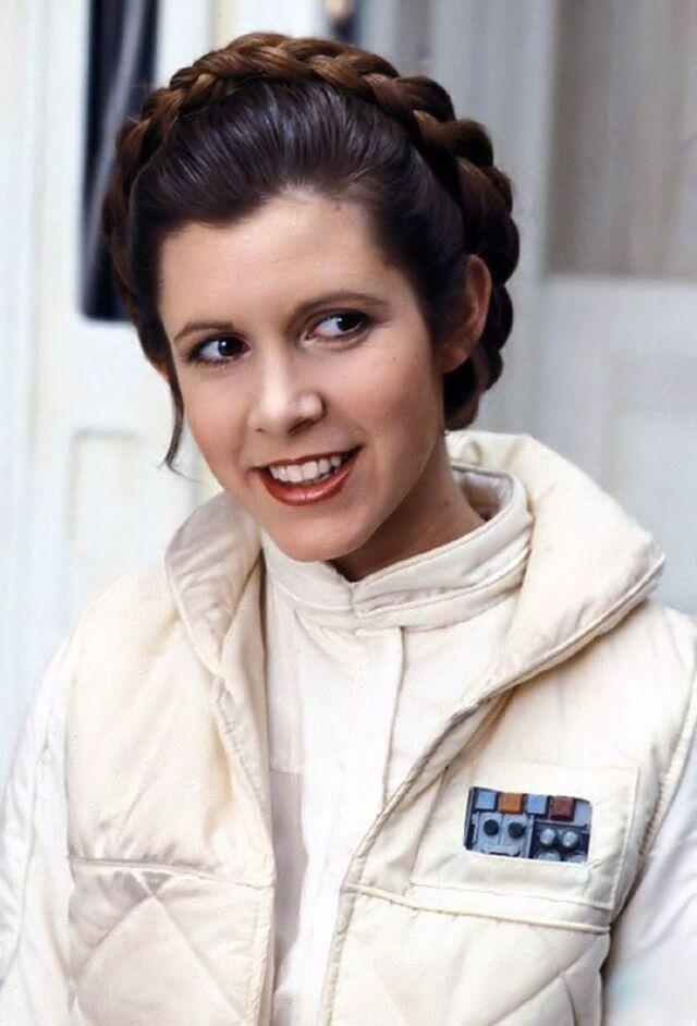 Carrie Fisher in the iconic Princess Leia braids, a timeless look that became a hallmark of her character in Star Wars. 