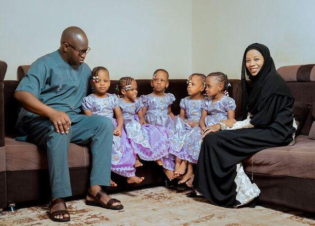 Les Nonuplés' beautiful girls, dressed in matching outfits, with their loving parents on a special family day.