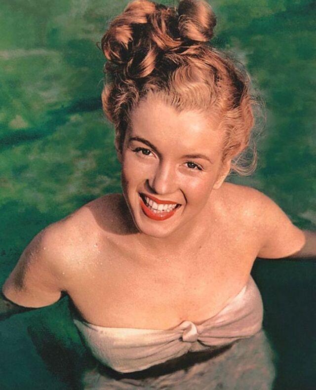 Norma Jeane smiling brightly while emerging from the water, her hair pinned up in soft curls—an image that highlights her youthful glow and effortless warmth.