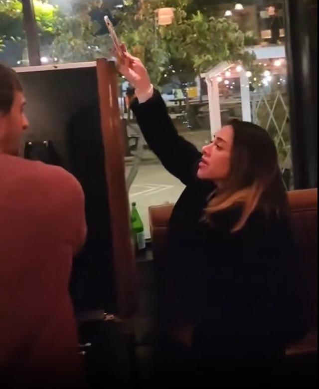 The woman continues to provoke, filming the heated interaction in the upscale restaurant.