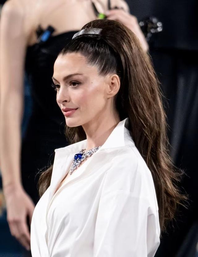 The high, sleek ponytail and sapphire-studded jewelry accentuate Hathaway's sophisticated transition into avant-garde couture.