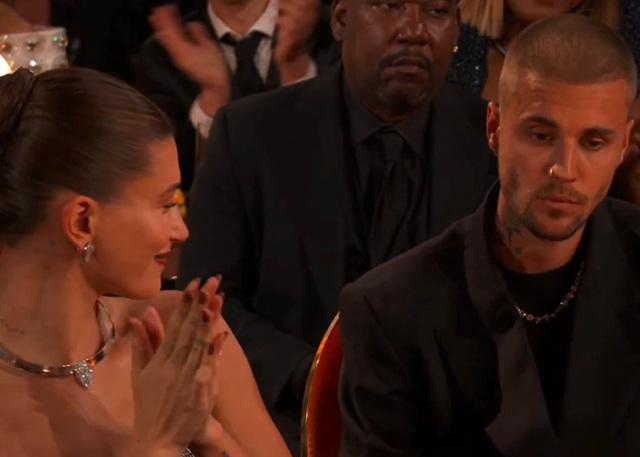 Hailey Bieber offers a polite, subtle smile as she navigates the table-side banter at the Grammy Awards."