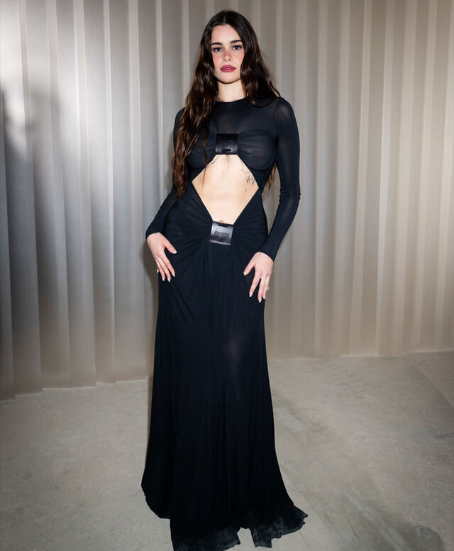 Barbie Ferreira poses in a sleek, floor-length black gown featuring avant-garde cut-outs.
