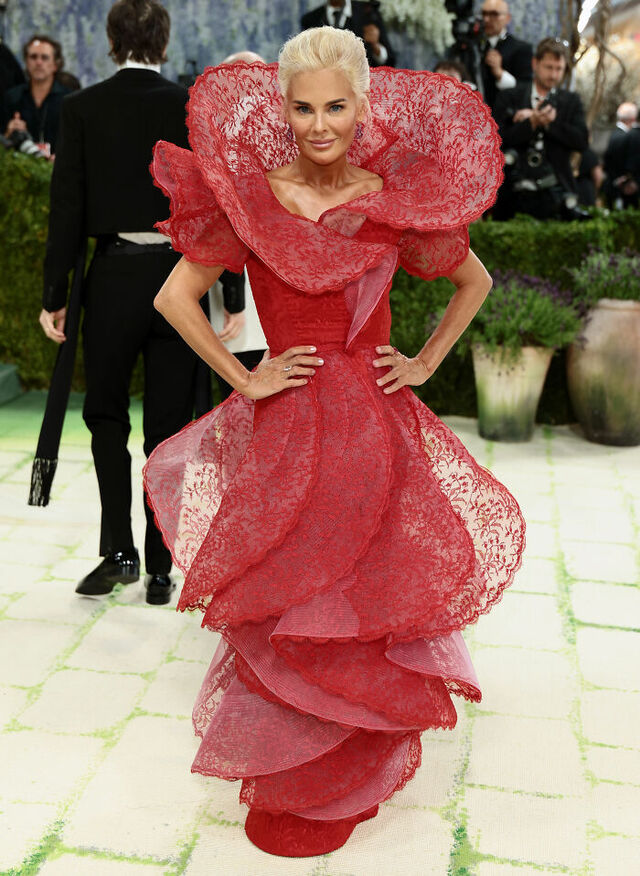 Christine Beauchamp: Structural crimson lace framing the face like a blooming flower.