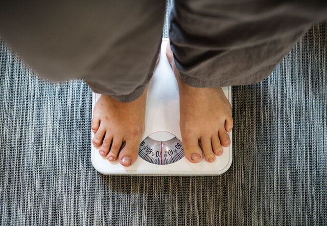 A top-down perspective of an individual standing on a traditional scale to track weight adjustments.