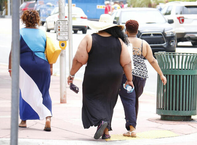 Pedestrians walking down a city sidewalk, illustrating the growing concerns over rising adult obesity rates.