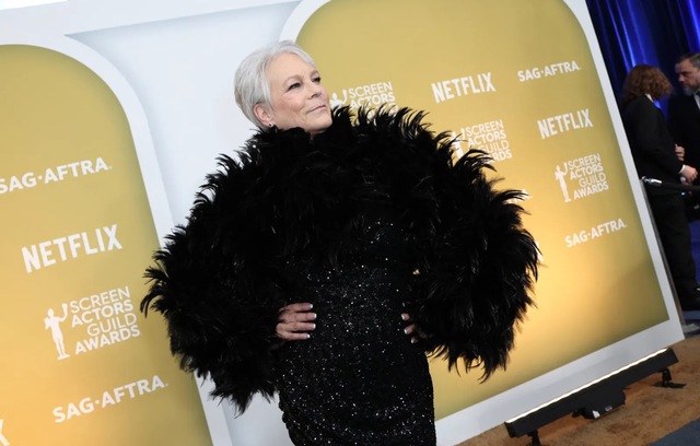 Rather than competing with the loud, structural statement of the feathers, Curtis opted for ultra-sleek hair, understated makeup, and minimal jewelry.